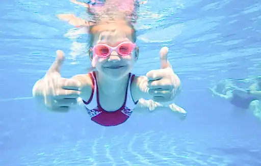 Nervous swimmers – how to help a nervous child to swim child under water giving thumbs up